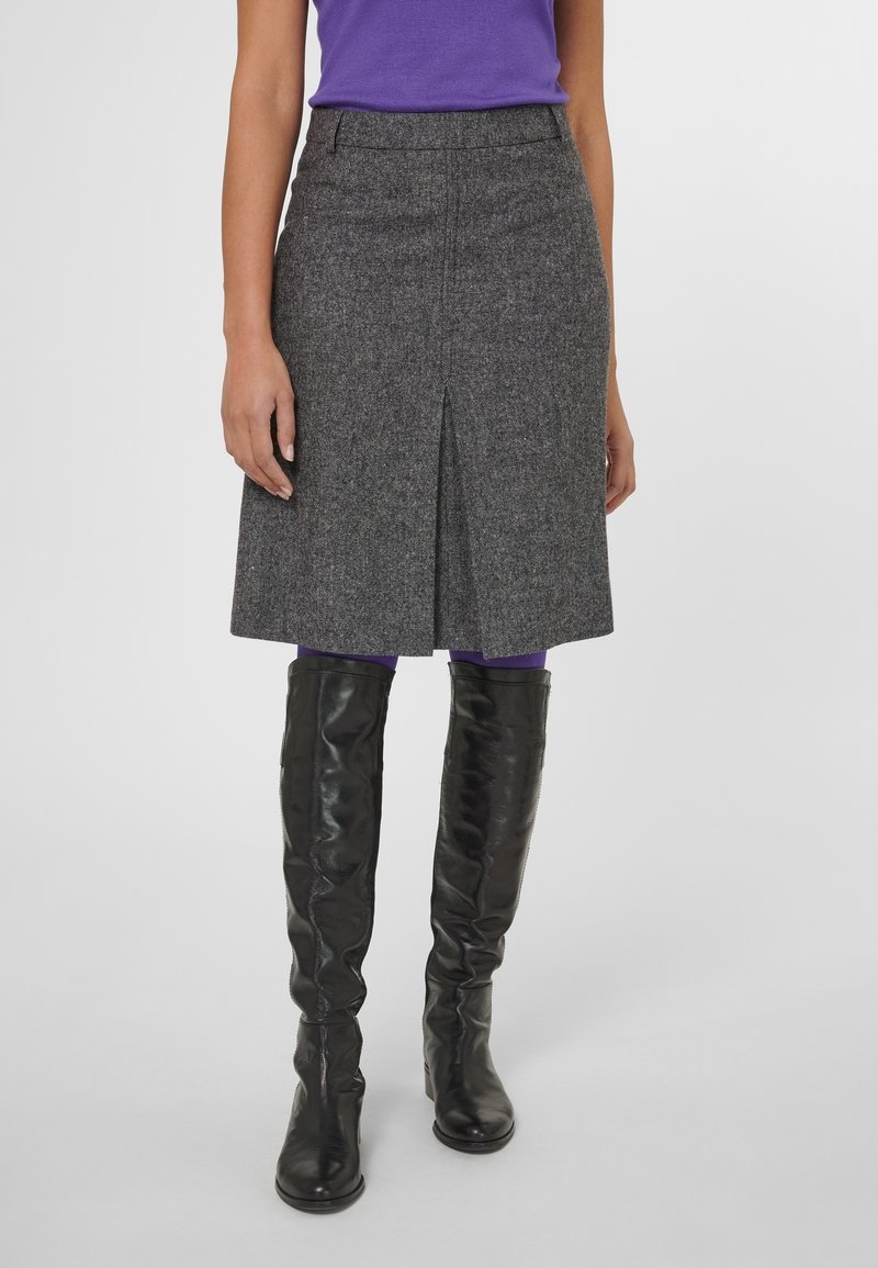Jupe gris en mélange de laine avec une coupe droite et une fente à l'avant, portée avec des bottes noires en cuir montantes jusqu'aux genoux. La texture est lisse et structurée.