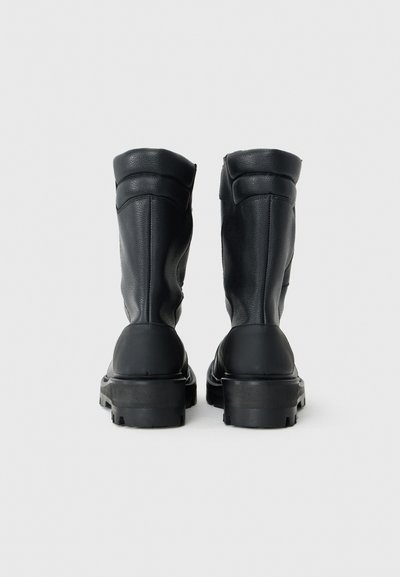 Schwarze Lederstiefeletten mit einer strukturierten Oberfläche, runder Zehenform und dicken Gummisohlen. Sie verfügen über eine verstärkte Ferse und eine Polsterung im oberen Bereich.