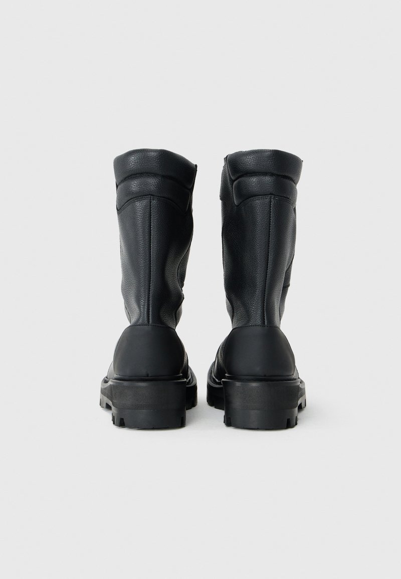 Bottines en cuir noir avec une finition texturée, bout rond et semelles en caoutchouc épaisses. Présentent un talon renforcé et un rembourrage supérieur.