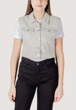 Gilet in denim grigio chiaro, tagliato, con collo a camicia, bottoni frontali e due tasche sul petto, indossato sopra una T-shirt bianca e jeans neri.