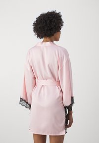 Rosa satinermorgenkåpe med lange, brede ermer, knyttet midje og svarte blonder på ermene og sidene, glatt tekstur.