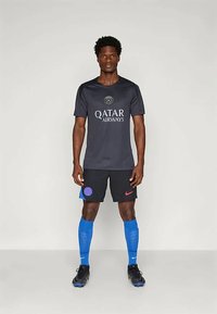 Fekete futballmez a "QATAR AIRWAYS" logóval, fekete rövidnadrággal, amely kék és rózsaszín díszítéssel rendelkezik, kék zoknival és fekete stoplis cipővel.