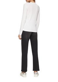 Witte lange mouwen shirt van lichte stof, gecombineerd met zwarte uitlopende jeans en sneakers met zilveren accenten. Achteraanzicht weergegeven.