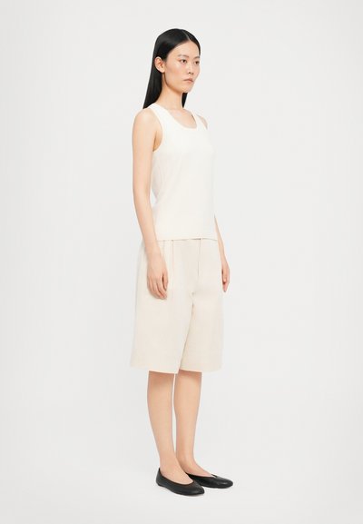 Lys beige ermeløs topp med rund hals og matchende beige shorts. Antrekket har en avslappet passform og enkelt, rent design.