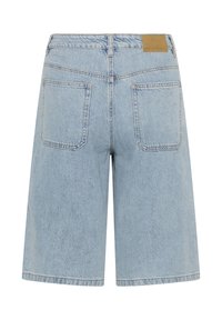 Short en jean bleu clair avec deux poches arrière, passants de ceinture et une petite étiquette en cuir de la marque sur la ceinture.
