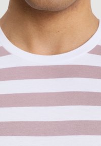 Camiseta a rayas con franjas horizontales en blanco y rosa claro, cuello redondo, material de algodón con una textura suave, escote ajustado.
