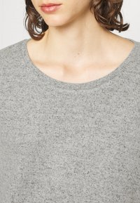 Gray textured sweater with a wide, round neckline and soft fabric. Shows midsection and neckline details, highlighting the fabric's pattern.