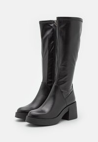 Botas de cuero negro hasta la rodilla con tacón ancho, que cuentan con un zipper lateral y textura suave. Diseño sencillo sin adornos adicionales.