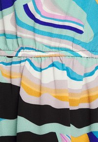 Colorful patterned fabric in shades of blue, green, pink, black, and yellow, featuring wavy lines and textured surface with gathering detail.