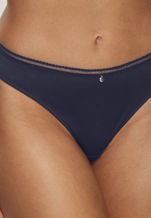 Slip da bikini blu navy realizzato in tessuto liscio, con dettagli in pizzo trasparente lungo la vita e una piccola decorazione metallica nella parte anteriore.