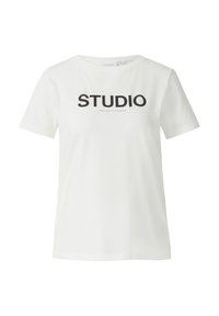 Biała bawełniana koszulka z krótkimi rękawami, okrągłym dekoltem i wyraźnym czarnym napisem "STUDIO" na przodzie. Lekko luźny krój.