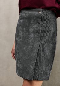 Harmaa corduroy-hame, jossa on sivureikä, vyötäröllä koristeelliset napit ja teksturoitu ribbikuvio. Eleganti ja rakenteellinen muotoilu.