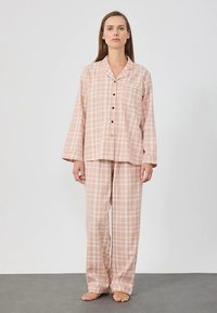 Ensemble de pyjama à carreaux roses en tissu doux, comprenant une chemise à col avec boutons, manches longues, et un pantalon assorti avec une taille élastique.