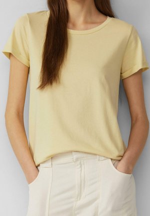 Kurzärmeliges T-Shirt mit Rundhalsausschnitt aus hellgelber Baumwolle. Weiche Textur, lässige Passform, mit umgeschlagenen Ärmeln und einem dezenten Nahtdetail am Saum.