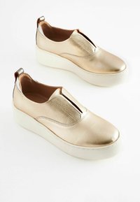 Scarpe slip-on metalliche dorate con tomaia testurizzata, suola platform bianca e pannelli laterali elasticizzati per una facile calzata.