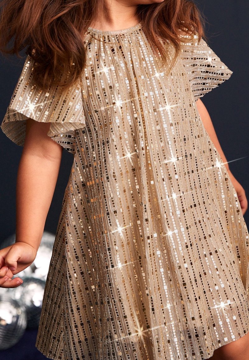 Robe en doré scintillant avec des rayures verticales, des manches flottantes transparentes et des sequins réfléchissants, créant un effet texturé et éblouissant.