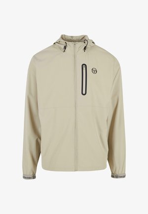 Beige szélálló dzseki cipzáras mellzsebbel, húzózsinóros kapucnival és rugalmas mandzsettákkal, melyen a logó a kézfejen található. Könnyű anyag.