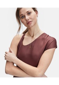 Burgunderfarbener, halbtransparenter Top mit einem Schulterdesign. Verfügt über eine glatte Textur und einen runden Ausschnitt. Goldene Kettenhalskette mit Anhänger.