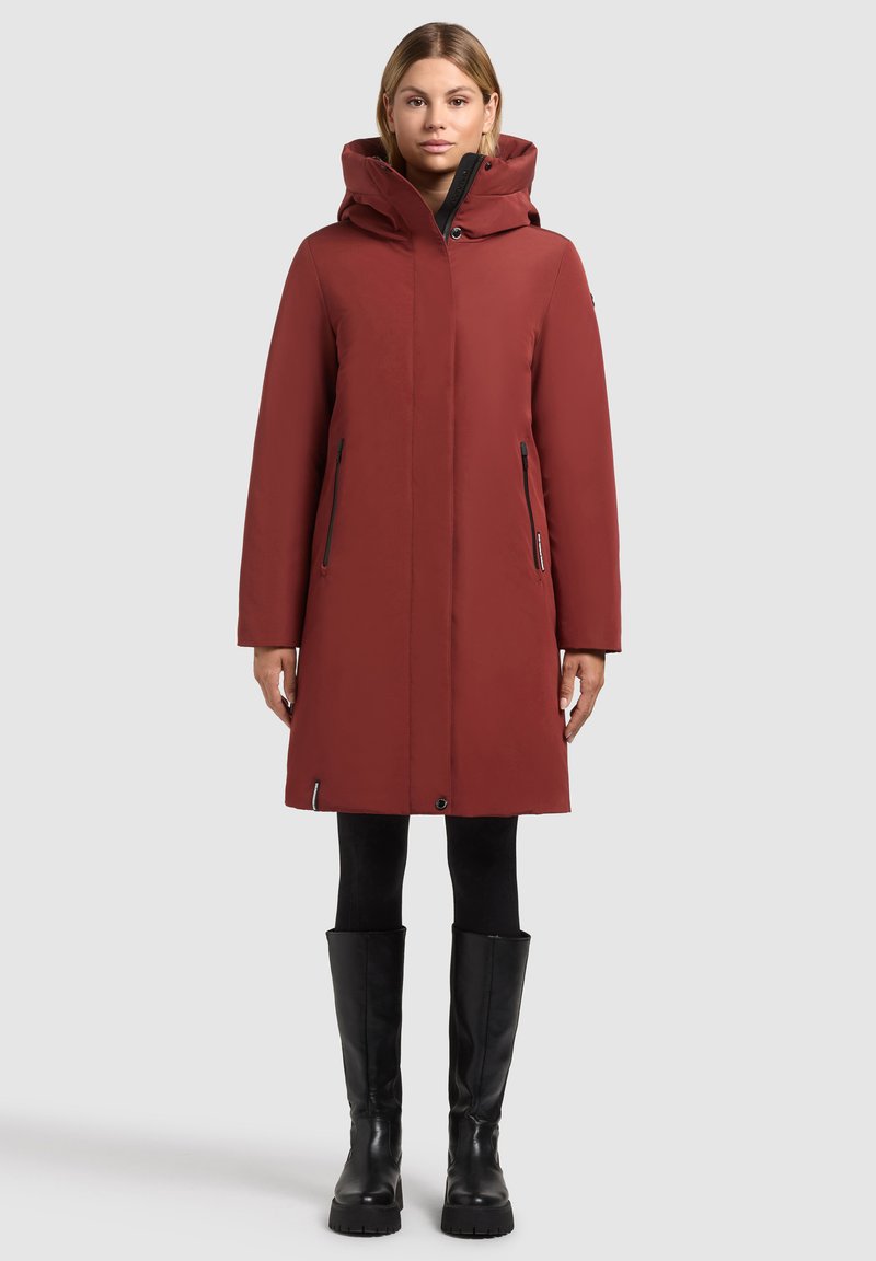 Parka imperméable rouge avec une capuche, des poches latérales zippées et une coupe droite. Elle possède une texture lisse et un ourlet ajustable.