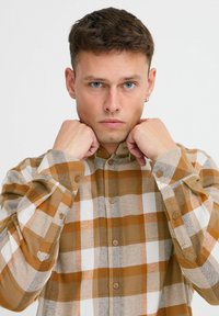 Braun- und cremefarbener karierteter Hemd mit Knöpfen, gefertigt aus einem weichen, strukturierten Stoff. Verfügt über einen Kragen und Knopfverschluss, mit langen Ärmeln.