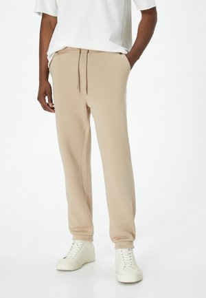Beige katoenen sweatpants met elastische boorden, zijzakken en een trekkoord in de taille. Gekocht met witte hoge sneakers.