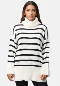 Pull à col roulé surdimensionné à rayures noir et blanc avec des manches longues, texture côtelée et col haut. Tissu en tricot doux.