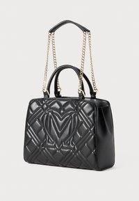Črna usnjena torbica z volnjenim vzorcem, vtisnjenim logotipom, dvema zgornjima ročajema in zlatimi dekorativnimi verigami. Pravokotna oblika z gladko teksturo.