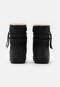 Botas de tobillo negras con un suave forro crema, que presentan una textura lisa, forma redondeada y cordones en la parte trasera para un ajuste y diseño ajustados.