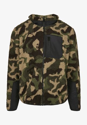 Jachetă din fâș cu un model de camuflaj în nuanțe de maro, verde și bej; are un buzunar pe piept cu fermoar negru și accente negre pe mâneci.