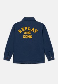 Sötétkék farmerdzseki hosszú ujjakkal, hátul sárga hímzett "REPLAY and SONS" felirattal, és gombos mandzsettával.