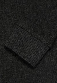 Tejido de punto negro con un detalle de puño acanalado. El material muestra un patrón texturizado, proporcionando una vista de cerca de la estructura tejida.