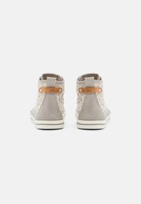 Šedé vysoké tenisky s texturovaným svrškem a výřezovými vzory, koženými akcenty v barvě tan a plochou bílou podrážkou s jemnými pruhy.