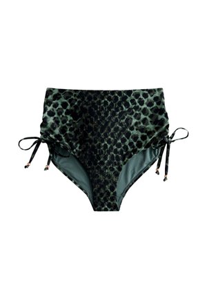 Kobieta nosząca zielone i czarne bikini z wysokim stanem w panterkę, z wiązaniem po bokach, na zewnątrz, blisko drewnianej poręczy.