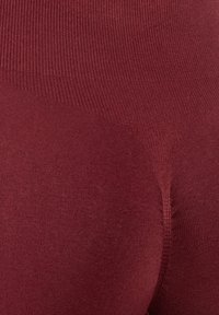 Bordeaux-kousen met een gladde textuur en een elastische geribbelde tailleband, met een naadloos ontwerp voor comfort en een nauwsluitende pasvorm.