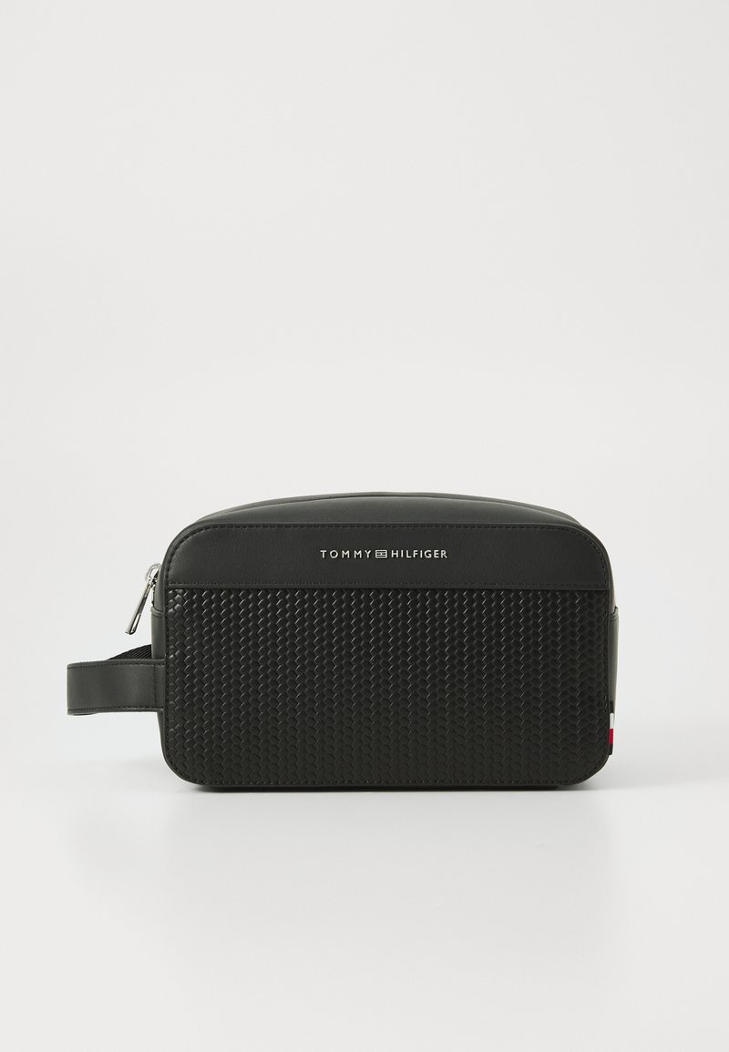 Black toiletry bag with a textured bottom and smooth top, features a zipper, and a side handle. Logo centered on the front.