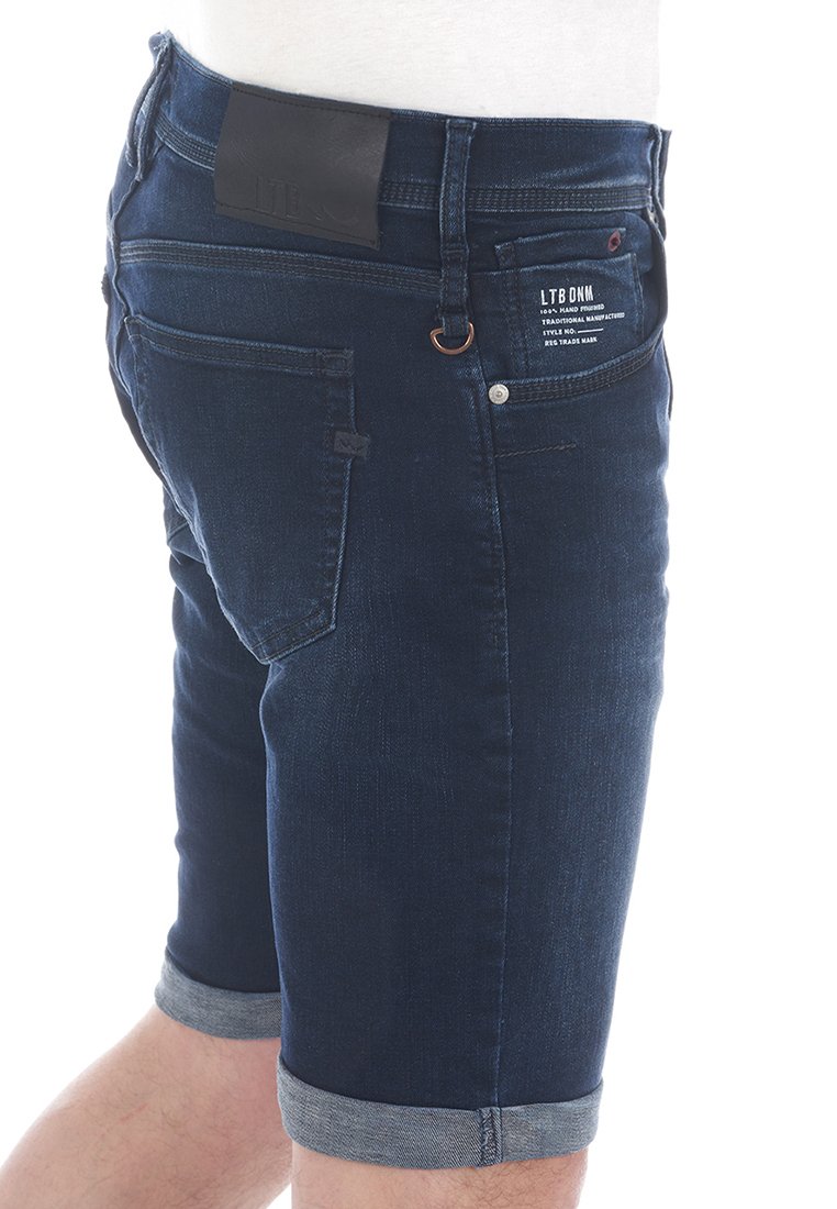 Pantalones cortos de mezclilla azul oscuro con dobladillo vuelto, que presentan un parche de cuero en la cintura y múltiples bolsillos, mostrando un diseño clásico.