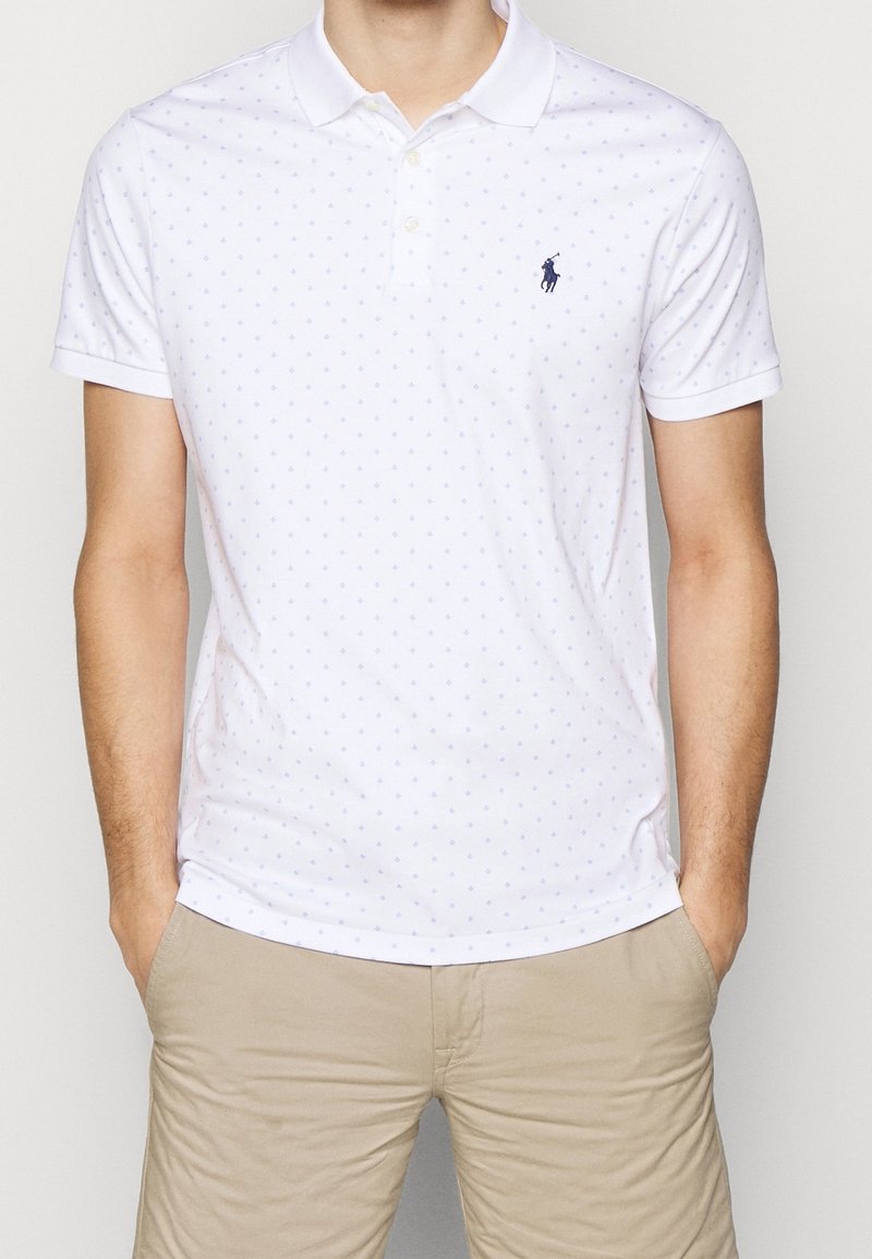 Witte polo shirt met lichtblauw stippenpatroon, korte mouwen en een drieknoopsluiting. Beschikt over een klein logo op de linkerborst.