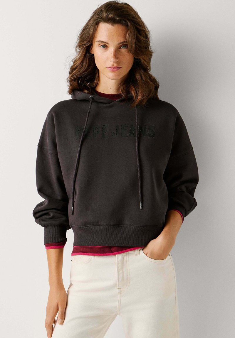 Dunkelgrauer Kapuzenpullover mit "Pepe Jeans"-Logo, gerippten Bündchen und lockerem Schnitt. Trägt man über einem bordeauxroten Oberteil und kombiniert mit hellen Jeans.