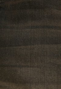 Mörk denimtyg med en grov textur och subtil lyster. Ytan visar svaga diagonala vävningar och en enhetlig färg genomgående.