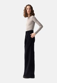 Szary, długi rękaw top o prążkowanej teksturze, zestawiony z czarnymi spodniami o wysokim stanie i szerokich nogawkach, które posiadają boczne kieszenie i gładkie wykończenie.