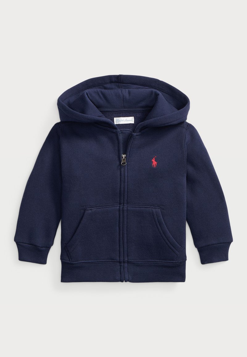 Sudadera con cremallera de color azul marino, hecha de algodón, con un bolsillo frontal, puños acanalados y un logo rojo bordado en el pecho.