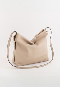 Beżowa skórzana torba na ramię o luźnym designie, z kontrastującym czarnym wykończeniem oraz odpinanym paskiem z złotymi akcentami.