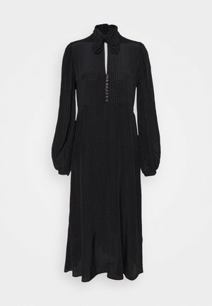 Černé šaty s vysokým výstřihem a detailem na zavázání, dlouhými nabíranými rukávy, knoflíkovou légou a tečkovanou strukturou po celém povrchu. Midi délka siluety.