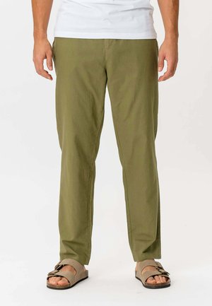 Olivengrønne bomuldsbukser med lige pasform, der har en glat tekstur og minimalistisk design. Kombineret med brune sandaler.