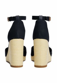 Navy canvas wedge heels with a woven beige rope base. Features an ankle strap with a small gold buckle. Closed back design.