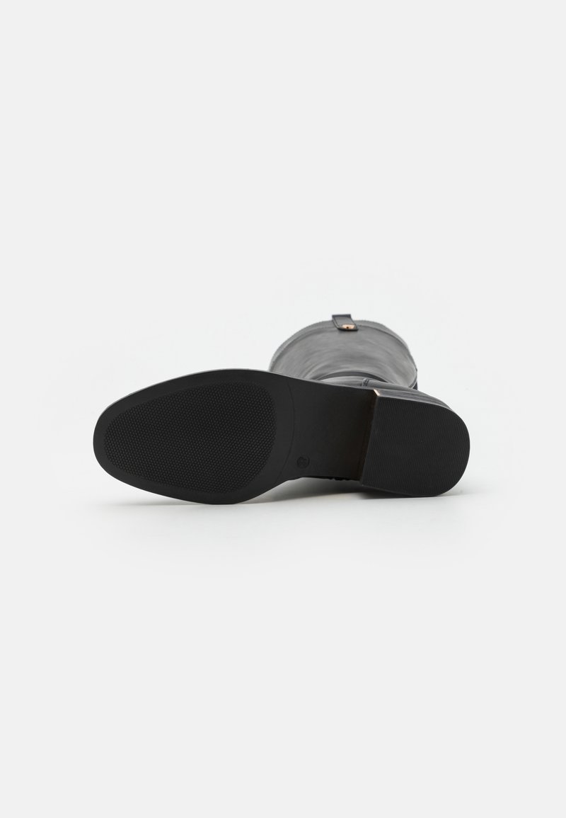Grijze leren enkelboot met een gestructureerde zwarte rubberen zool. Heeft een gladde afwerking en een kleine decoratieve riem aan de achterkant.