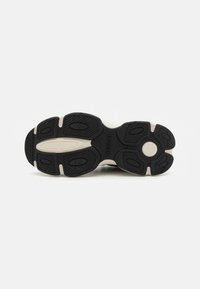 Semelle en caoutchouc noire avec des rainures à motifs et intermédiaire blanc. Présente le nom de la marque "REPLAY" embossé sur le côté. Texture lisse sur l'ensemble.