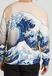 Camicia a maniche lunghe con un motivo a onde multicolori, prevalentemente blu e bianco, con barche visibili su uno sfondo chiaro.