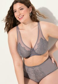 Lingerieset met kantafwerking in zachtgrijze meshstof, met een diepe V-hals en bloemmotieven, inclusief bijpassende hoog-getailleerde slips.