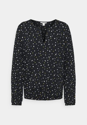 Zwarte blouse met lange mouwen en een gespleten halslijn, voorzien van een verspreid patroon van kleine witte en gele abstracte vormen.
